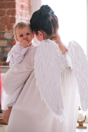 Beautiful mother and her toddler daughter wearing angel costumes. High quality photoの写真素材