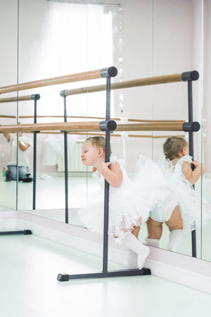 Portrait of a cute baby ballerina sitting near the ballet barre putting on shoes. videoの写真素材
