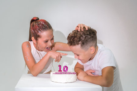 Brother and sister having fun and eating cake in studio. High quality photoの写真素材