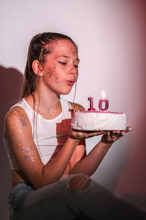 Girl blowing out candles with the number 10 on the cake. High quality photo