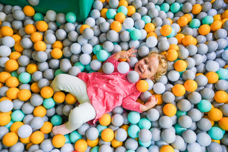 Girl playing in the pool with colored balloons in the children's center. High quality photoの写真素材