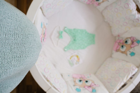 A baby's nursery with a white crib and a baby doll. The crib is surrounded by pillows and a blanketの写真素材
