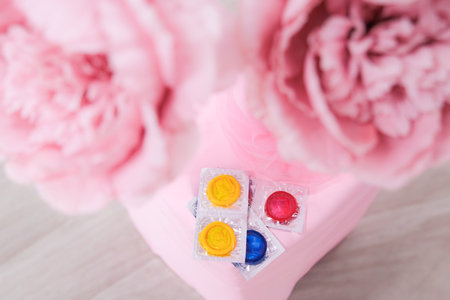 condoms are lying on a background of pink peonies, space for text. High quality photoの写真素材
