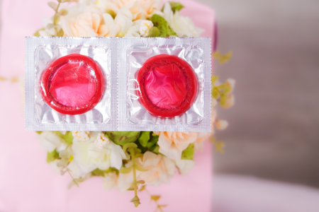condoms are lying on a background of pink peonies, space for text. High quality photoの写真素材