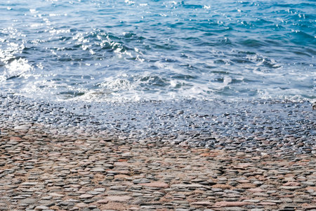 A rocky beach with a body of water in the background. The water is calm and the rocks on the beach are scattered throughout the scene. Scene is peaceful and serene, with the waterの写真素材