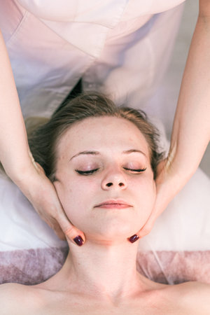 A woman is getting a massage, with her head on a table. The woman is smiling and she is enjoying the massageの写真素材