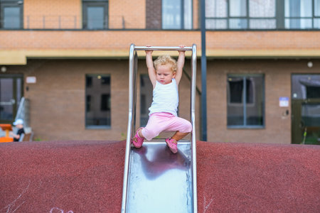 Young girl playing and sliding down a slide. High quality photo
