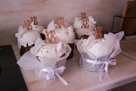 Moscow, Russia, 04/18/25. A row of white cupcakes with XB and XB on them. The cupcakes are decorated...