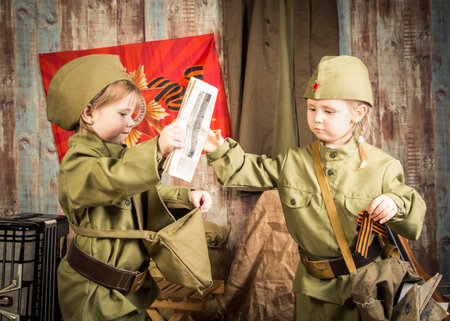 Two children dressed in military uniforms are playing with a passport. Scene is playful and lightheartedの写真素材