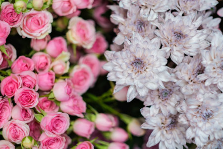 A beautiful arrangement of pink and white flowers, including roses and daffodils, is displayed in a way that creates a sense of balance. The pink roses are in the foregroundの写真素材