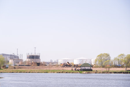 A group of people are sitting in a small green and white pavilion by a body of water. The scene is...