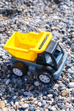 A toy truck is sitting on a pile of rocks. The truck is yellow and black, and it is a dump truck. The scene is simple and unadorned, with the focus on the toy truck and the rocksの写真素材