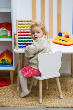 moscow, russia, 09/28/2024 A small caucasian kid sits at a desk in a classroom, looking back at the camera. Early childhood education and elementary learning concept.の写真素材