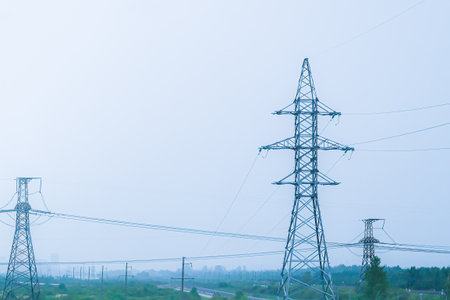Moscow, Russia, 08/18/2025 High voltage electrical power pylons with long transmission lines against a clear sky. Urban infrastructure delivering energy.の写真素材