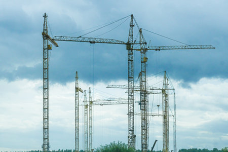 Moscow, Russia, 08/18/2025 Multiple yellow construction cranes stand tall against an overcast sky. Heavy machinery on a building site for urban development.の写真素材
