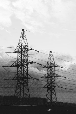 Moscow, Russia, 08.18.2025 Two dramatic electricity pylons silhouetted against a cloudy sky. Power lines for energy transmission. Industrial landscape.の写真素材