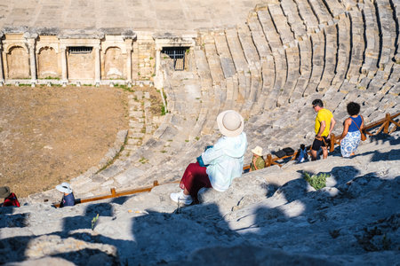 pamukkale, Turkiye, 08.07.2025 Woman in hat sitting in ancient amphitheater in Turkey. Tourist...