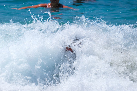 A woman in a bikini is swimming in the sea, half submerged in foamy waves, a concept of summer...