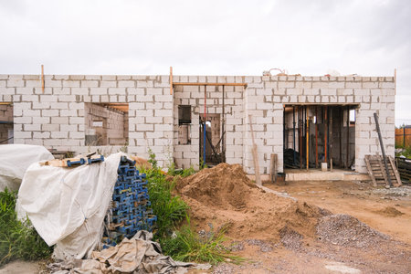 Russia, Saint Petersburg, 08/23/2025 Unfinished house with white brick walls. Modern home building process with construction materials on site. Progress of new residential dwelling.の写真素材