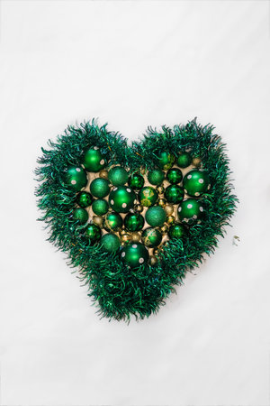 Heart shape made of green festive garland and assorted Christmas ornaments on white background. Holiday decoration concept.の写真素材