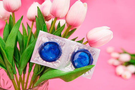 condoms on tulip flowers, pink background. High quality photo