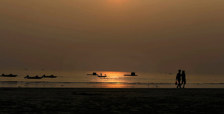 Silhouette of couple walking at beachの写真素材