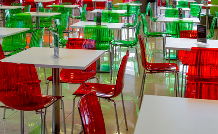 Empty tables, green and red chairs in a cafeの写真素材