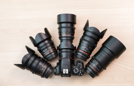Digital SLR camera and a few interchangeable manual lenses. The equipment for filmmaking. The wooden table.の写真素材