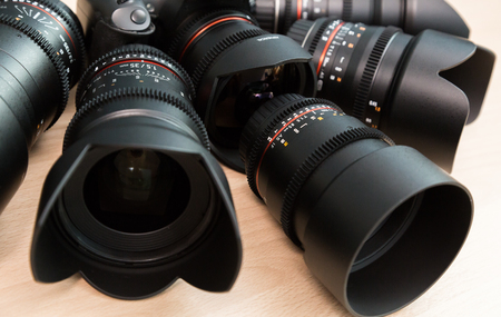 Digital SLR camera and a few interchangeable manual lenses. The equipment for filmmaking. The wooden table.の写真素材