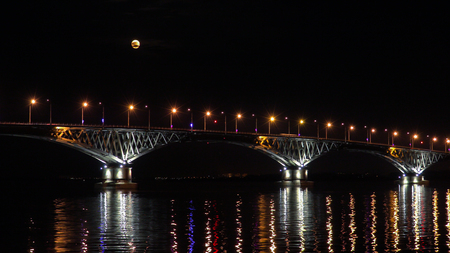 Full moon rises over the bridge. Road bridge between the cities of Saratov and Engels, Russia. The Volga River. The evening lights of cars and street lightsの写真素材