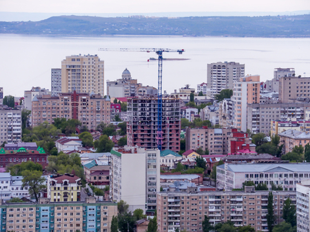 View of the city of Saratov from the mountain. The urban landscape, infrastructure, tenement houses, public buildings and streets, the Volga river on the horizon. Russian province.の写真素材