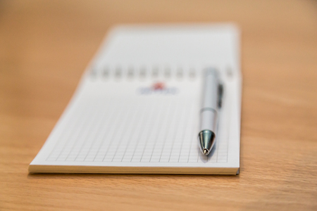 A notebook and ballpoint pen lying on a wooden table.の写真素材