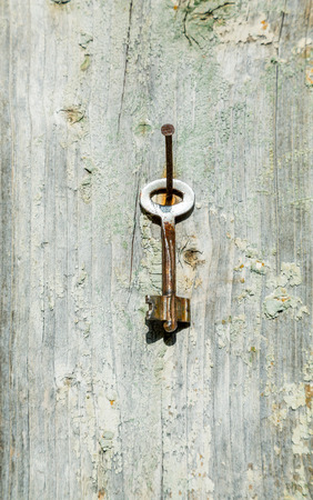 The key hanging on a nail on a wooden wall. Textured backgroundの写真素材