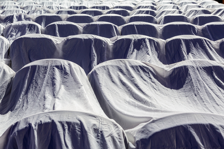 Chairs in the auditorium, covered with a white cloth to protect from dust and dirt.の写真素材