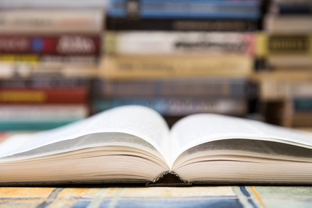 A stack of books with colorful covers. The library or bookstore. Books or textbooks. Education and reading. Open book in the foreground.の写真素材