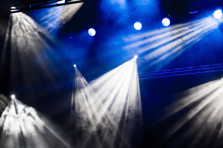 White and blue light rays from the spotlight through the smoke at the theater or concert hall. Lighting equipment for a performance or show.の写真素材