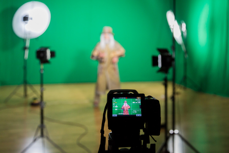 Shooting the movie on a green screen. The chroma key. Studio videography. Actor in theatrical costume. The camera and lighting equipment.の写真素材