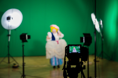 Shooting the movie on a green screen. The chroma key. Studio videography. Actress in theatrical costume. The camera and lighting equipment.のeditorial素材