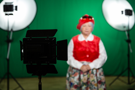 Actress in theatrical costume in a Television Studio. Green screen and chroma key. Lighting equipment and filming equipment.の写真素材