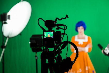 The actress in the studio on a green background. Video of the interview. Cameras and lighting equipment.の写真素材