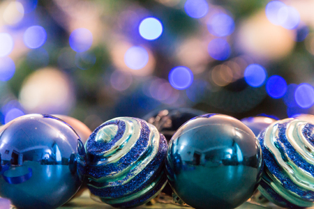 Decorated Christmas tree with blue lights. Christmas balls in the foreground. Blurred image of a tree in the background.の写真素材