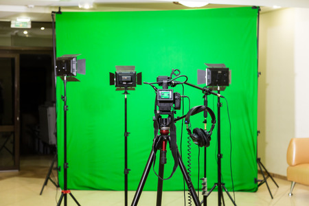 The camera on the tripod, led floodlight, headphones and a directional microphone on a green background. The chroma key. Green screenの写真素材