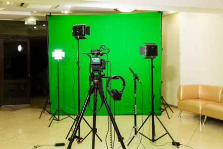 The camera on the tripod, led floodlight, headphones and a directional microphone on a green background. The chroma key. Green screenの写真素材