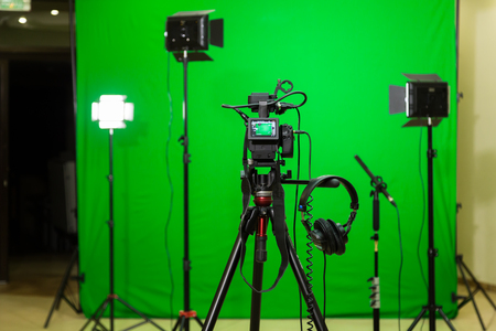 The camera on the tripod, led floodlight, headphones and a directional microphone on a green background. The chroma key. Green screenの写真素材
