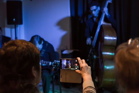Video shooting with your smartphone. Filming of the concert. Musicians playing the double bass and electric guitar.の写真素材