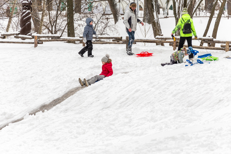 Saratov / Russia - March 8, 2018: Children ride with an ice slide. Winter vacation. Outdoor activity. Winter day in the city Park.のeditorial素材