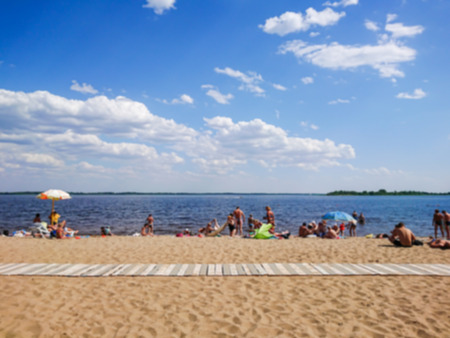 Abstract blurred image. Defocused lens, bokeh. People swim in the sandy beach. On a sunny summer day.の写真素材