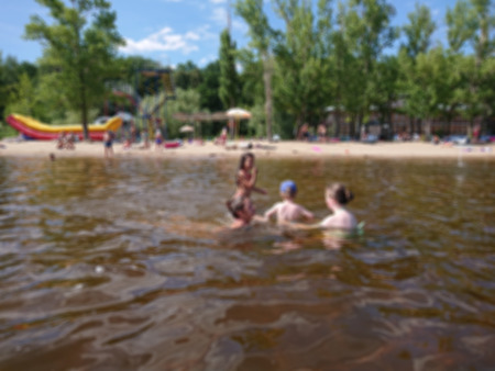 Abstract blurred image. Defocused lens, bokeh. People swim in the sandy beach. On a sunny summer day.の写真素材