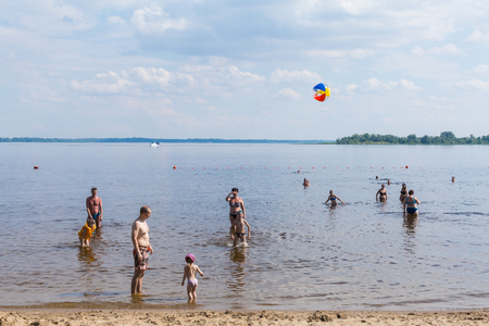 Sandy river beach. On a sunny summer day. Children and adults play ball in the water.の写真素材