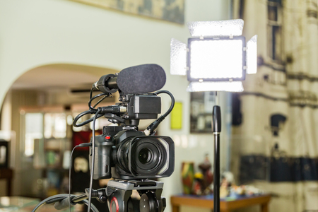 Shooting a report in the interior. Video equipment: camera, on-camera microphone gun, led lighting device, tripod.の写真素材